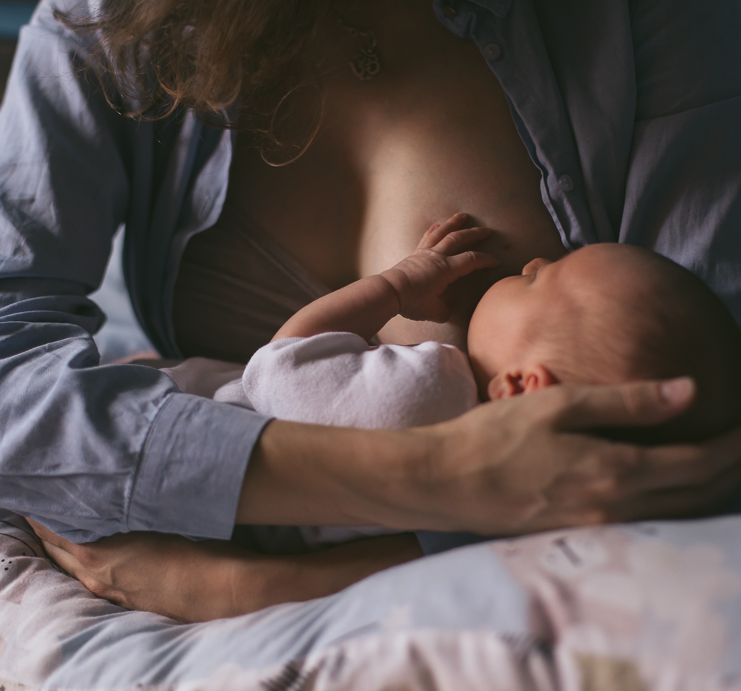 Young,Mother,Breastfeeds,Her,Newborn,At,Home.,Low,Key,Dark